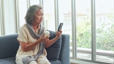 Yaşlı bir kadın kızına sohbet videosu danışmanlığı hakkında soru sormak için akıllı telefon kullanıyor. İlacını alıyor çünkü ilaç etiketindeki küçük metni anlamıyor..