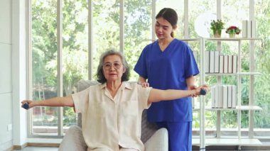 Kadın fizyoterapist, omzu ve kolu ağrıyan yaşlı bir kadını tedavi ediyor. Hemşire ağrıyı rahatlatıcı bir masajla tedavi ediyor, yaşlı bir kadının moralini düzeltiyor..