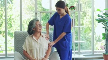 Kadın fizyoterapist, omzu ve kolu ağrıyan yaşlı bir kadını tedavi ediyor. Hemşire ağrıyı rahatlatıcı bir masajla tedavi ediyor, yaşlı bir kadının moralini düzeltiyor..