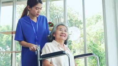 Kadın hemşire, iyileşme odasında tekerlekli sandalyedeki yaşlı hasta bir kadına bakıyor. Hemşire yaşlı ve hasta kadının endişelerini dindirmesine ve akıl sağlığını düzeltmesine yardım ediyor..
