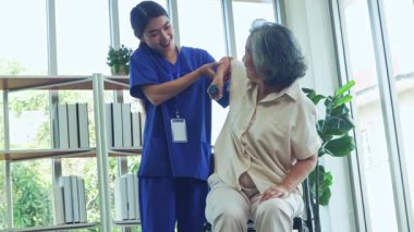 Kadın fizyoterapist, yaşlı bir kadın hastaya kas distrofisi eğitimi veriyor. Kas egzersizleri yapıyor. Kaslarını tedavi ediyor ve beriberi 'yi engelliyor..