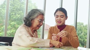 Yaşlı bir anne ile Asyalı kızı arasında mutlu bir gün. Masada oturup yapboz oynarken eğleniyorlar..