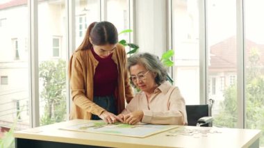 Yaşlı bir anne ile Asyalı kızı arasında mutlu bir gün. Masada oturup yapboz oynarken eğleniyorlar..