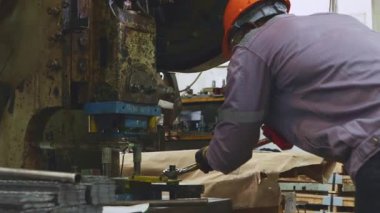 Erkek fabrika torna operatörü metal pul makinelerini çalıştırırken fındıkları sıkı tutmak için uzun kollu İngiliz anahtarı kullanır ve güvenlik için dikkatlice çalışır..