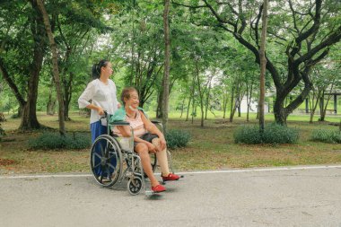 Kızının, bacakları kesilmiş ve tekerlekli sandalyede tedavi görmüş yaşlı bir kadını umursaması engelliliğini azaltmak için protez bacağını tutuyor..