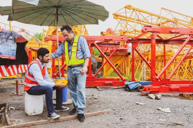 Stres yorgunluğundan muzdarip bir vinç montaj tesisinde çalışan erkek işçi, omzunu sempatik bir şekilde tutan meslektaşı tarafından rahatlatıldı:.