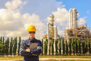 Sert şapkalı erkek mühendis, radyo raporlama önleyici bakım işleriyle birlikte basınçlı petrol ve doğalgaz boru hattının açık havada güvenlik denetimi yapan mezura üzerindeki çalışma platformunu teftiş ediyor..