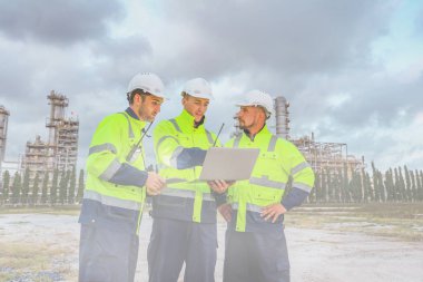 Erkek mühendis, rafineri gaz ayırma ve petrol kimyasalı atölyesinin güvenlik çalışma alanını inceler ve sisli bir şekilde dışarıdaki rafineri alanında güvenlik koruması sağlar.