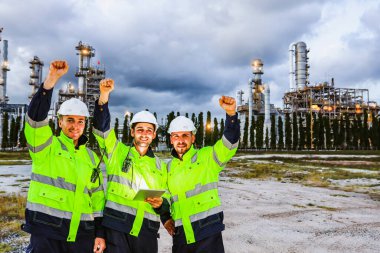 Ekip çalışması başarılı olduğu için mutluyuz: Güvenlik mühendisleri, petrol rafinerisi ve petrol endüstrisi alanında bir takım olarak çalışarak, temiz ve mutlu bir şekilde yumruklarını kaldırdılar..