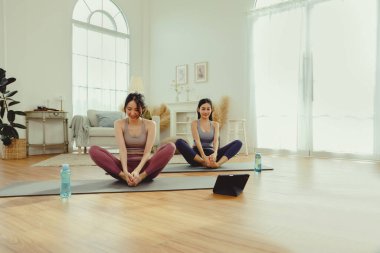Spor kıyafetlerinde sağlıklarına dikkat eden iki sağlıklı Asyalı kadın yoga minderinde kollarını ve dizlerini bir arada uzatarak spor salonunda egzersiz yapıyorlar: konsept yaşam tarzı..