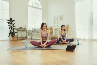Spor kıyafetlerinde sağlıklarına dikkat eden iki sağlıklı Asyalı kadın yoga minderinde kollarını ve dizlerini bir arada uzatarak spor salonunda egzersiz yapıyorlar: konsept yaşam tarzı..