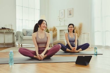 Spor kıyafetlerinde sağlıklarına dikkat eden iki sağlıklı Asyalı kadın yoga minderinde kollarını ve dizlerini bir arada uzatarak spor salonunda egzersiz yapıyorlar: konsept yaşam tarzı..