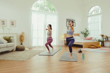 Spor kıyafetlerinde sağlıklarına dikkat eden iki sağlıklı Asyalı kadın yoga minderinde kollarını ve dizlerini bir arada uzatarak spor salonunda egzersiz yapıyorlar: konsept yaşam tarzı..