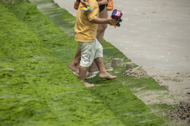 Cha-am, Tayland, 3-12-2023. Bir kadın, oyuncak taşıyan bir çocuğa yosun dolu bir merdivenden inerken yardım eder..