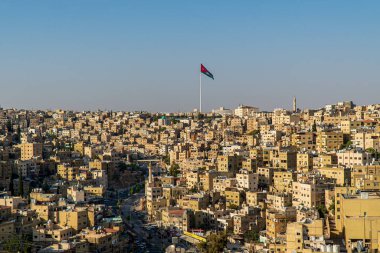 Ürdün 'ün başkenti Amman. Şehir merkezindeki evlerin üzerinde kocaman bir Ürdün bayrağı dalgalanır..