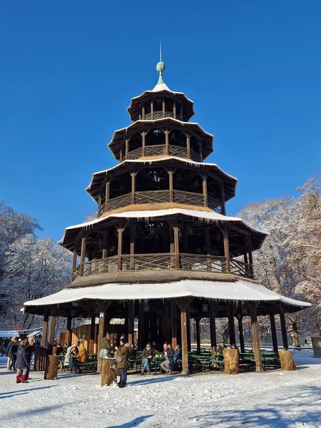 17 Aralık 2022 'de Almanya' nın Münih kentindeki İngiliz Bahçesi 'ndeki Çin Kulesi' nin Noel pazarında 17 Aralık 2022 'de güneşli ve karlı bir kış gününde insanlar toplandı..