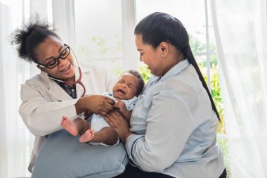 African doctor woman using a stethoscope, checking the respiratory system and heartbeat of a 1-month-old baby newborn, who is half Nigeria half Thai, to Infant health care concept.