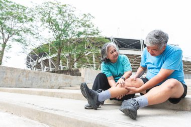 Asyalı yaşlı bir çift, karısı kocasının bacak kaslarını sakatlıklarla sıkıyor, egzersiz yüzünden kramplar yaşıyor. İnsanlara emeklilik yaşı ve kas krampı konsepti.