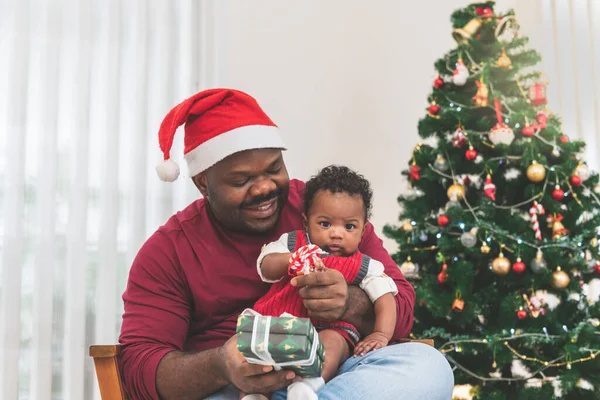 African family, 4-month-old Nigerian baby newborn son and father, smiling and happy together, with blur background of Christmas tree, to African family on holiday and baby infant concept.