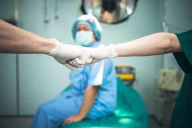 Doktorların ekip çalışması hastaya sinerji tedavisini göstermek için elleri kullanıyor. Kadın hasta geçmişi bulanık, ameliyathanede. cerrahi konseptinde sağlık ve sinerji işbirliğine