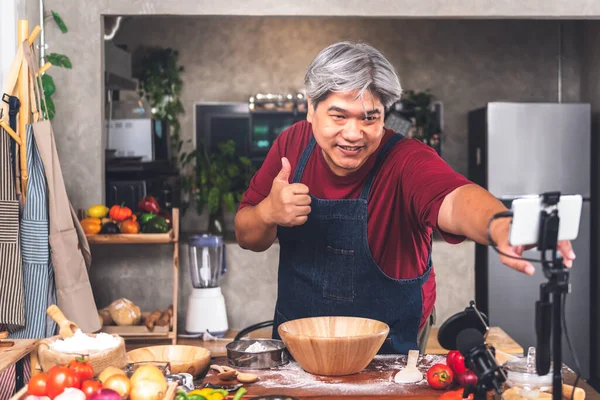 an Asian fat man standing in the kitchen, preparing equipment to make content about pizza homemade. to Influencer Marketing and social media concept.