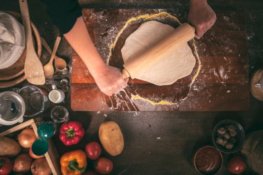 person rolling pizza dough by using the device is a rolling pin. to help pizza dough evenly and sized as desired. to kitchen and food homemade concept.