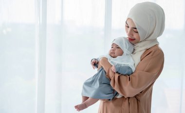 Müslüman bir ailenin portresi, kucağında bebek taşıyan çekici bir anne 1 aylık. Beyaz arka planda duruyor. Müslüman aileye ve yeni doğan bebek kavramına.