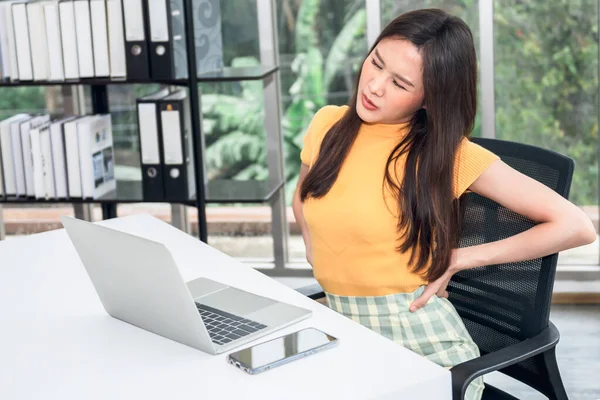 Stock image Asian businesswoman is tired, fatigued and has waist pain from sitting and using the computer for a long time, to businesspeople and office syndrome concept.