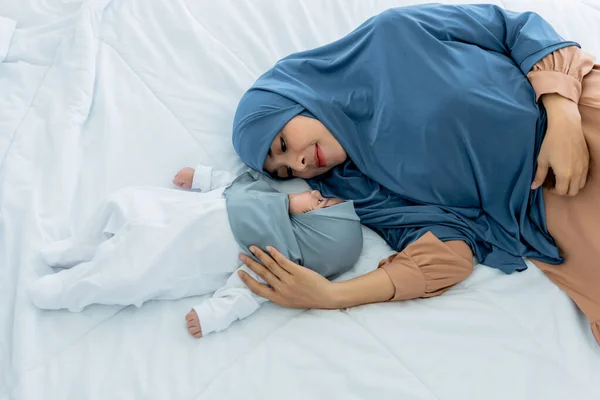 穆斯林家庭 亚洲迷人的母亲和两个月大的女婴 是半个尼日利亚的半泰国人 他们都很放松 躺在白色的床上 伊斯兰家庭和婴儿概念中的关系 — 图库照片