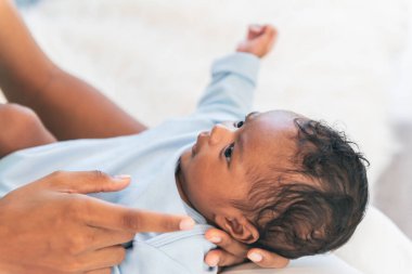 Yarı Nijerya, yarı Tayland, 1 aylık yeni doğmuş bebek, annesi kucağındayken gülümseyen ve ona bakan, aile ve yeni doğan bebek kavramı..