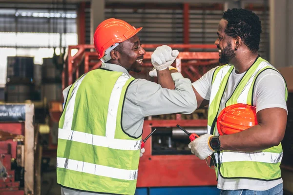 2 male worker African American, working in a factory, Shaking hands and happy that the work done together is successful, concept to teamwork of workers in industrial factories.