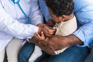 Steteskop kullanan Afrikalı doktor kadın, solunum sistemini ve yarı Nijeryalı yarı Taylandlı yeni doğmuş bir bebeğin kalp atışlarını kontrol ediyor..