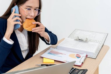 Çalışırken yemek yediği Asyalı iş kadını. Çünkü işi bitirmek için acele ediyordu. İş ve iş için o kadar meşguldü ki konsepti yemek için vaktiniz bile yoktu..