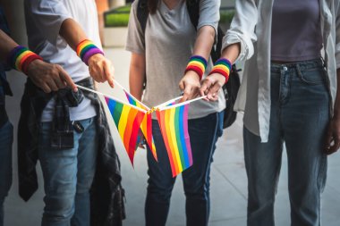 Bir grup homoseksüel insan bileklerini takmış ve LGBT sembolünü gösteren bir bayrak tutuyorlar, LGBT insanları için eşit haklar için mücadele ediyorlar..