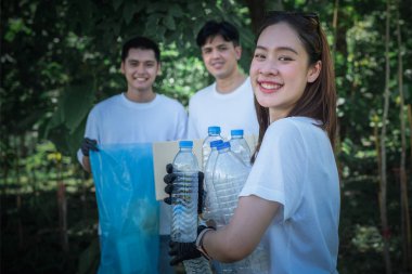 Parktaki çöp ve plastik şişeleri toplamaya yardım eden Asyalı bir gönüllü grup. Dünya konseptini kurtarmak için gönüllü olmak..