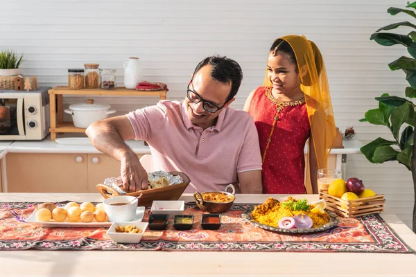 an Indian family, father and daughter in the kitchen They happy together while eating Indian food, placed on the table, to family and Indian food concept.