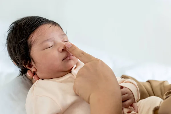 A mother touches her daughter\'s nose with her fingers, is a 1-month-old baby newborn, with white background. to relationship family and baby newborn concept.