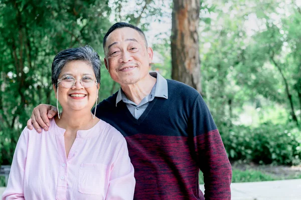 Portrait images, an Asian elderly couple standing in the park, they are smile and happy together. to elderly and good health in retirement age concept.