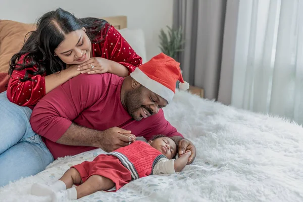 African family, Nigerian father and Asian mother looking, smile happily while looking  baby newborn son is 4-month-old was sleeping in white bed, to relationship in family and baby concept.