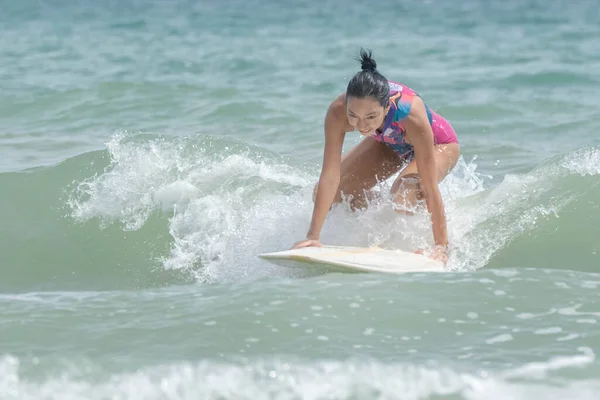 an Asian women Surfboarding in the sea with small waves happily, to people and surfboard concept.