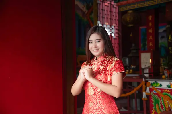 Portrait of a beautiful Asian woman wearing a red cheongsam Pay your respects and ask for blessings inside the shrine. It is believed to be a Chinese woman praying for good luck.