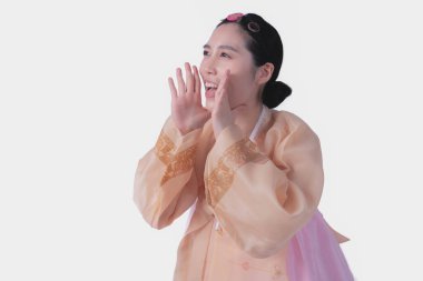 Geleneksel Hanbok giyen güzel Koreli kız elini ağzına koyar ve çığlık atar. Sağlık hizmetleri ve şarkı söylemek için beyaz arka planda.