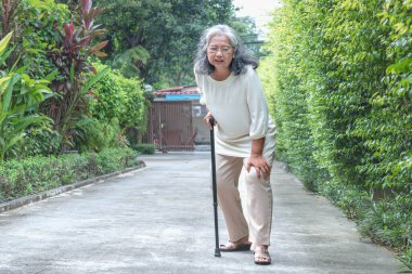 Yolda yürüyen yaşlı bir kadın. Osteoporoz yüzünden diz ağrısı çekiyor. Emeklilik ve sağlık hizmeti kavramı.