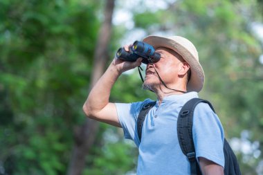 Asyalı turistler yürüyüş için sırt çantası taşıyorlar, kuşları izlemek için kamera kullanıyorlar, doğa yürüyüşü yapıyorlar. Emeklilikten sonra mutlu