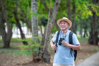 Asyalı turistler, Tayland 'da ulusal bir parkta bir orman parkını araştıran sırt çantalarını taşırken ağaçlardaki kuşları tespit etmek için dürbün kullanıyorlar. Bitki ve hayvan araştırmacıları kavramları