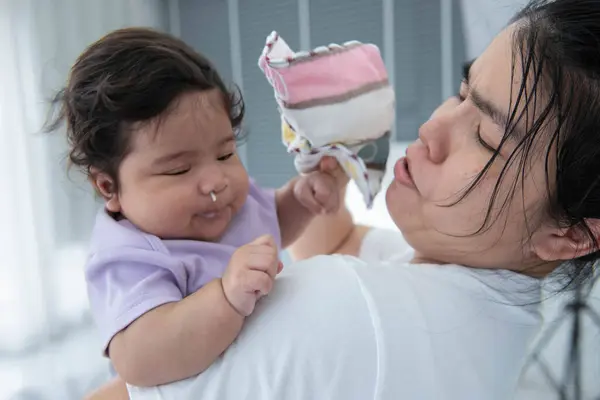 stock image A mother holds a baby who has milk coming out of his nose because he choked on excess milk while holding him.