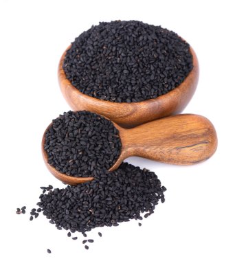 Tahta kase ve kaşıkta siyah kimyon tohumları, beyaz arka planda izole. Bir yığın siyah nigella tohumu. Nigella sativa