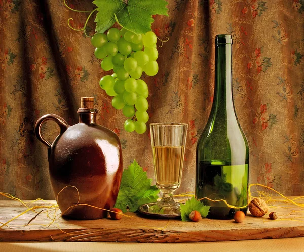 白ワインボトルと緑のブドウの背景を持つガラス — ストック写真
