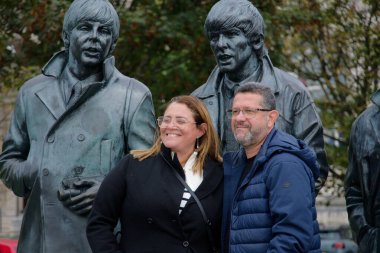 Couple posing with Beatles statues in Liverpool, UK clipart