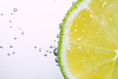Beyaz arka planda baloncuklu limon diliminin makro fotoğrafı. Tazelik ve sağlıklı yaşam tarzı kavramı. Yüksek kalite fotoğraf